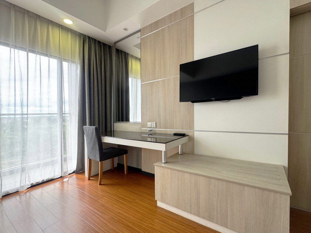 Premier King Room at Livingston Hotel Sandakan showing bed, TV, mirror, and vanity desk
