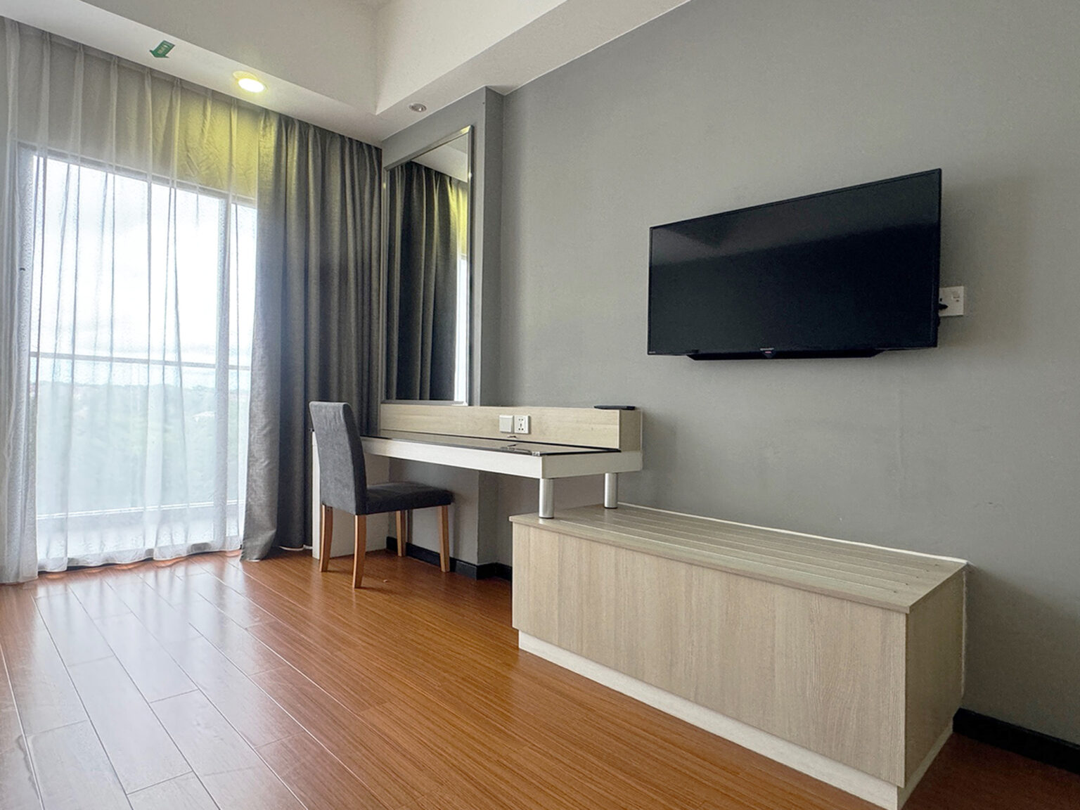 Deluxe Twin Room at Livingston Hotel Sandakan showing mirror, chair, table, TV, and luggage area