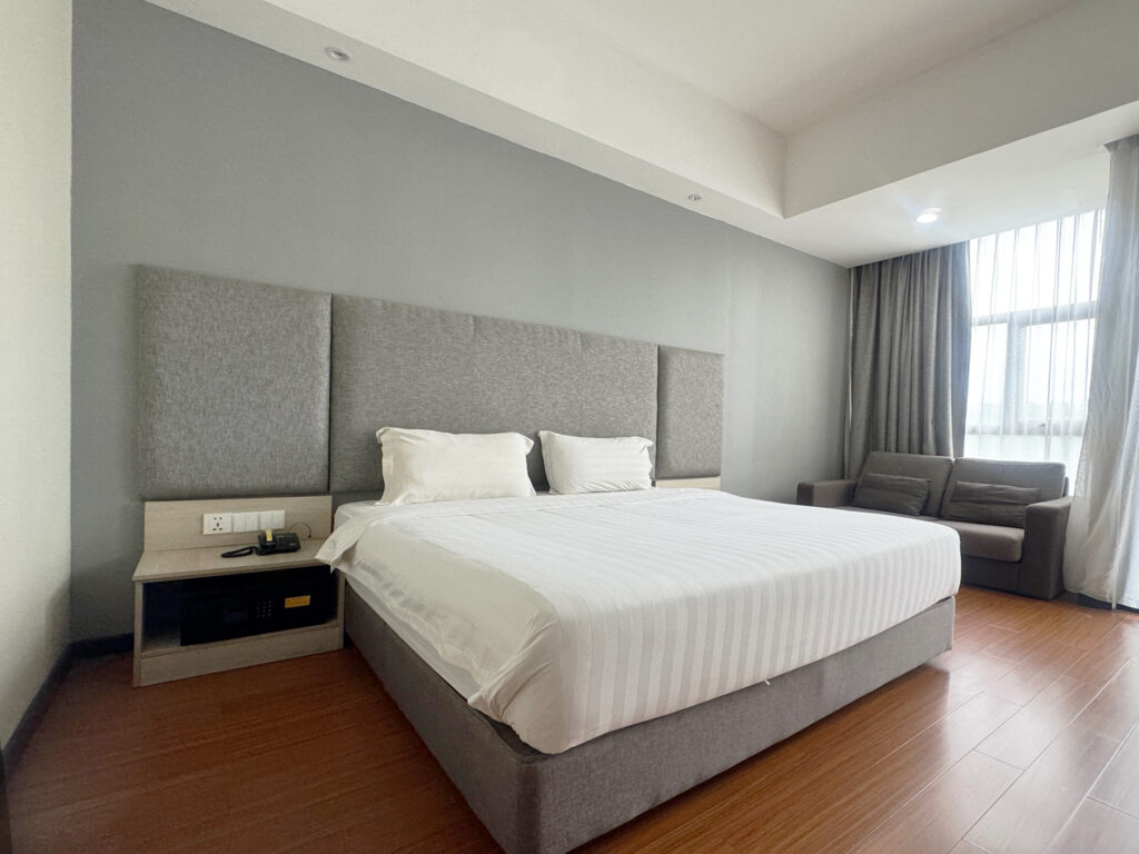 Bed area in Deluxe King Room at Livingston Hotel Sandakan showing bedside light and safety box