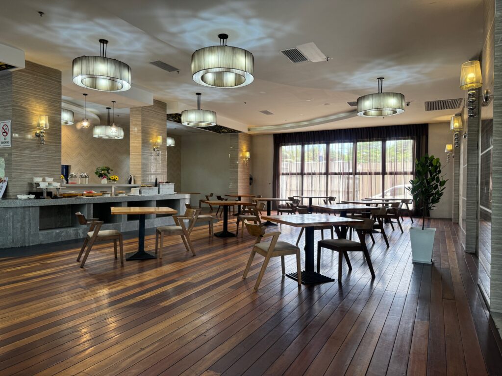 Interior of The Living Delight Restaurant at Livingston Hotel Sandakan showing tables, chairs, and ambient lighting