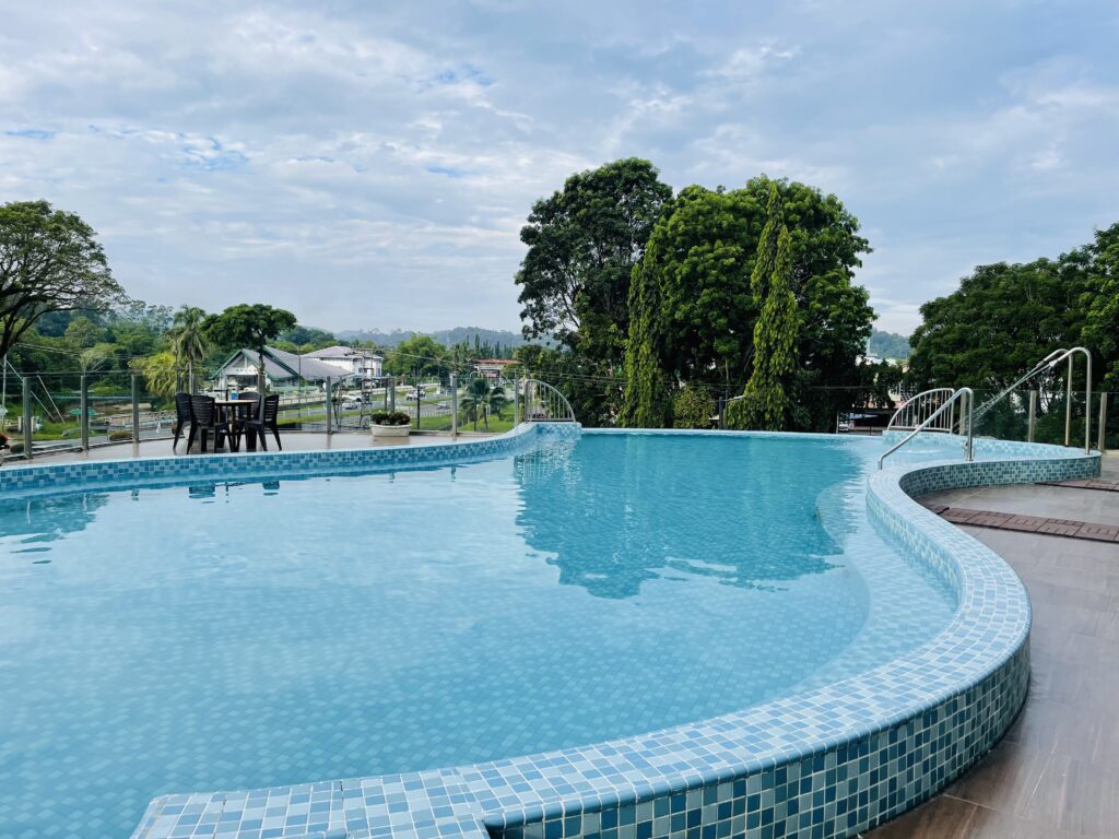 Curved infinity pool at Livingston Hotel Sandakan with trees and scenic view