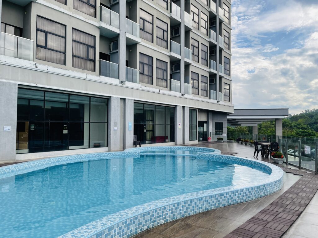 Swimming pool area at Livingston Hotel Sandakan showing adult and kids pools with glass fence and function hall in background