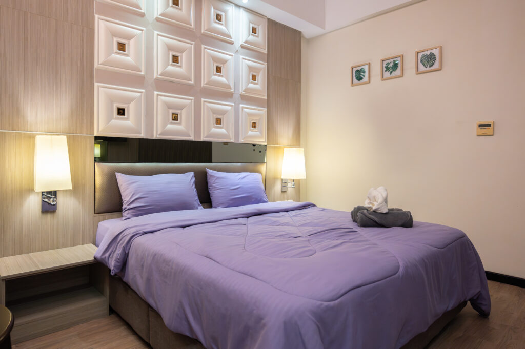 Caribbean Suite at Livingston Hotel Sandakan showing bed with diamond-patterned cushioned headboard, TV, and flower decoration