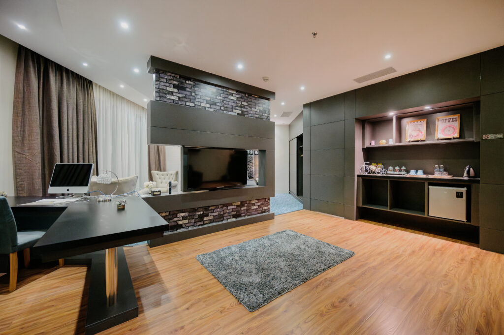 Living room area of Executive Suite at Livingston Hotel Sandakan showing rotatable TV, sofa, and working desk with Apple desktop