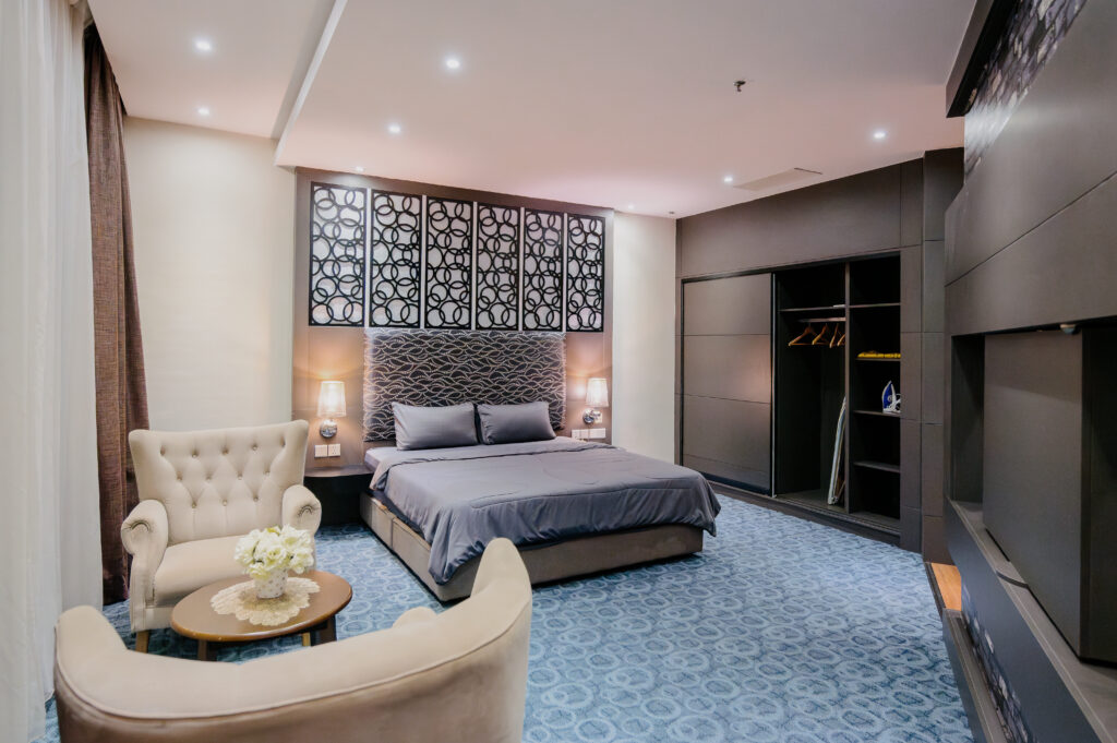 Executive Suite at Livingston Hotel Sandakan showing bed with high ceiling panels, single-seat sofas, and large wardrobe