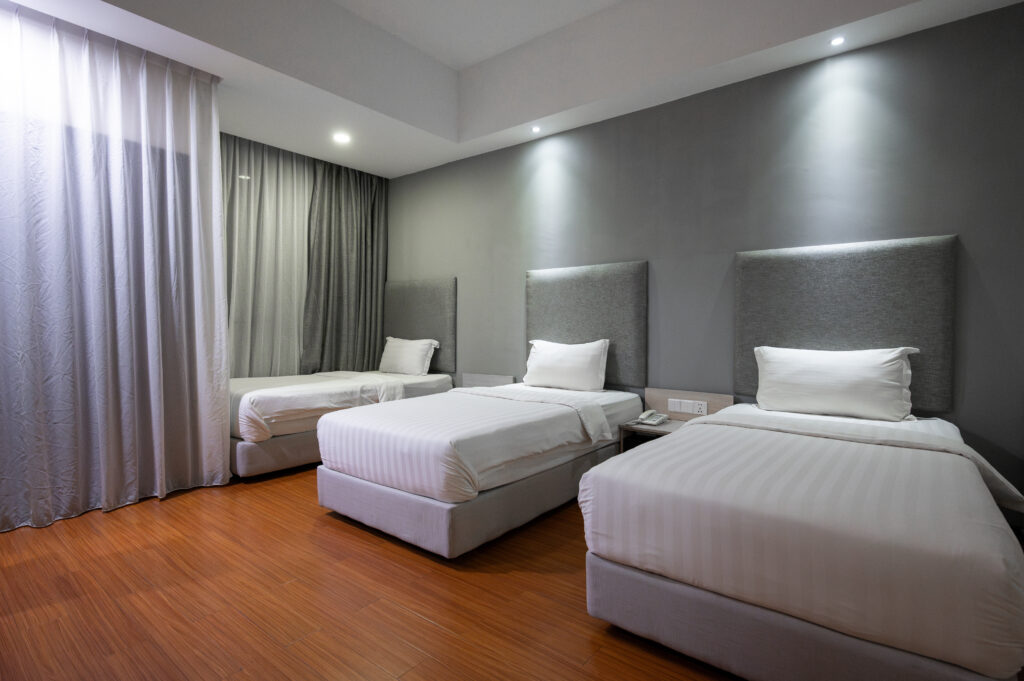 Interior of Deluxe Triple Room at Livingston Hotel Sandakan showing beds and bedside lighting