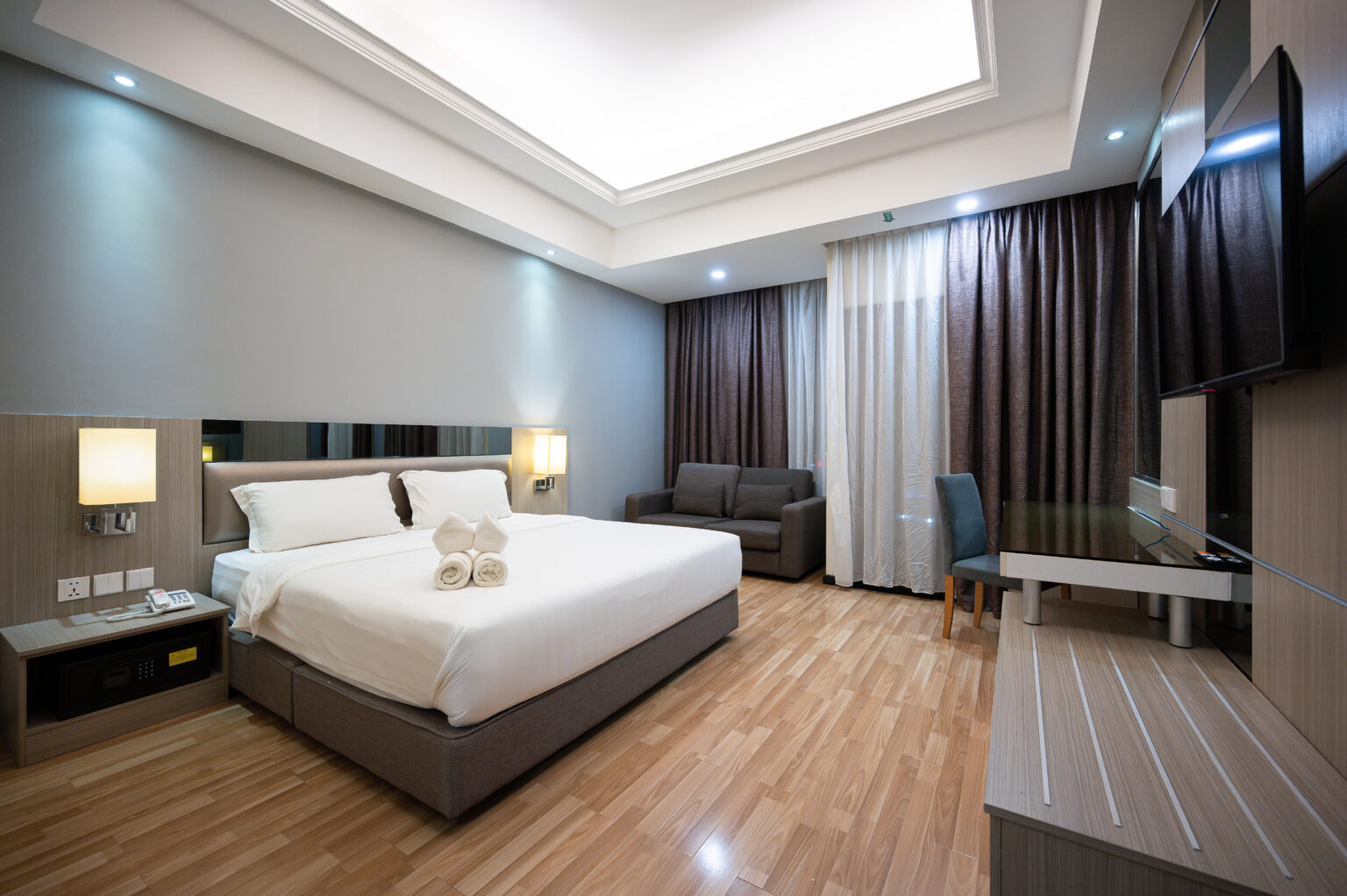 Interior view of Premier King Room at Livingston Hotel Sandakan showing bed, sofa, balcony, and modern decor