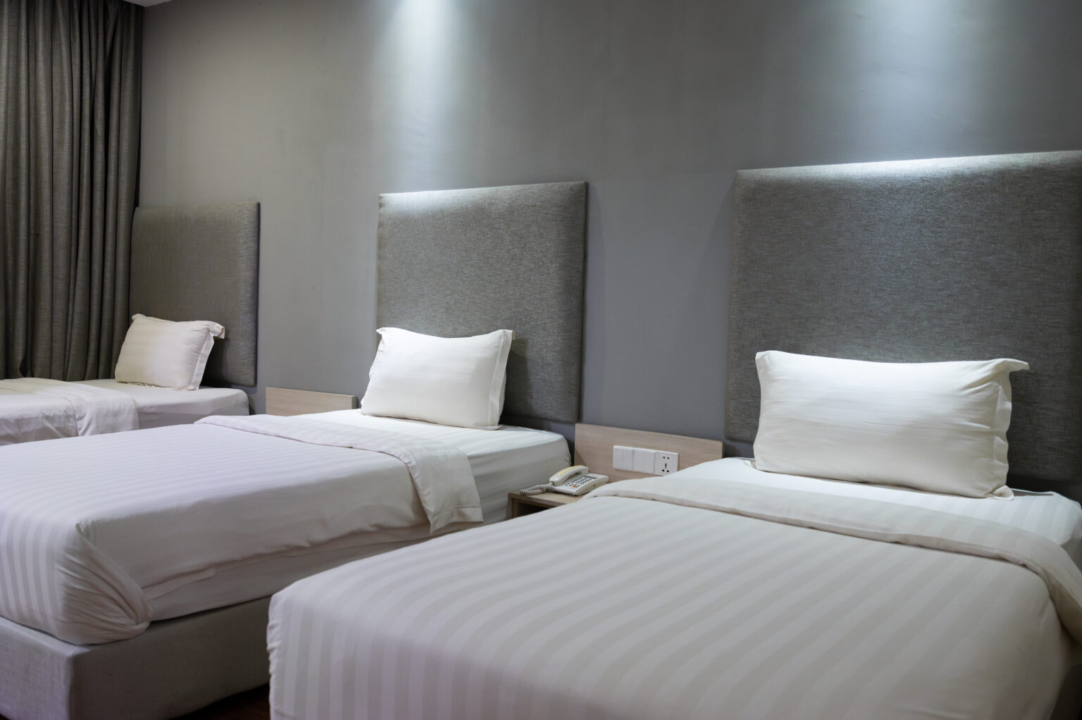 Deluxe Triple Room at Livingston Hotel Sandakan showing beds, bedside lighting, and amenities