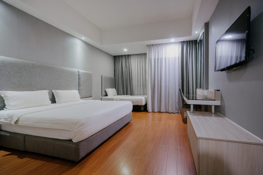 Deluxe Junior Room at Livingston Hotel Sandakan showing king and single bed, TV, and luggage area