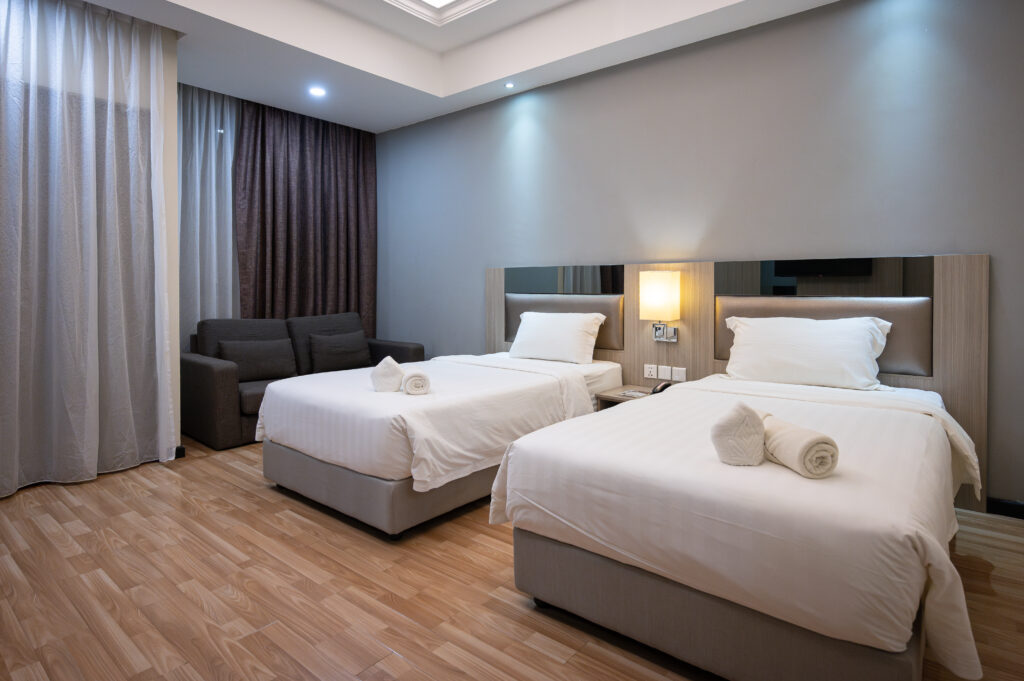 Interior view of Premium Twin Room at Livingston Hotel Sandakan showing two beds, sofa, balcony, and modern decor