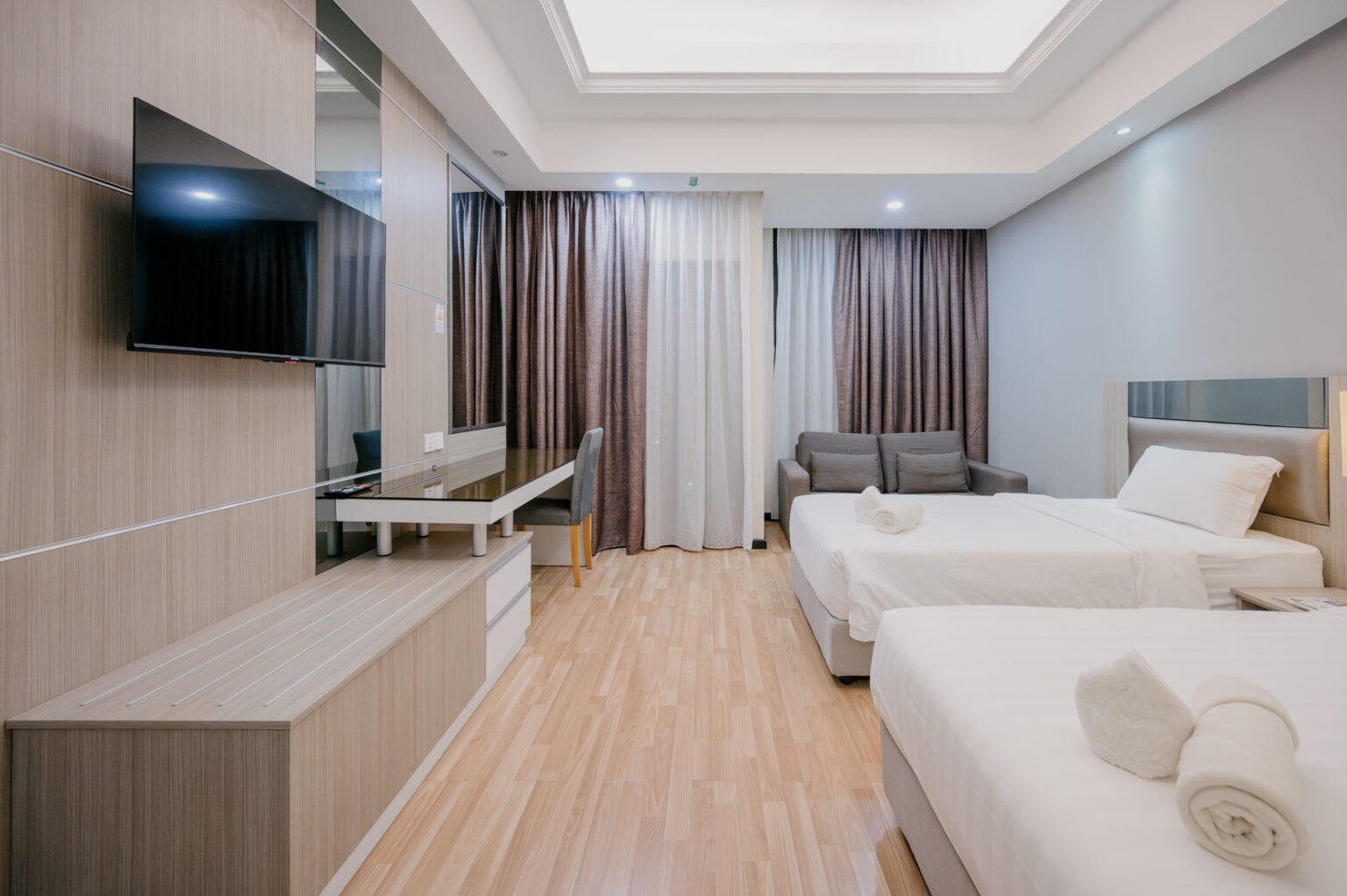 Interior of Premium Twin Room at Livingston Hotel Sandakan showing twin beds, sofa, balcony, luggage area, and TV