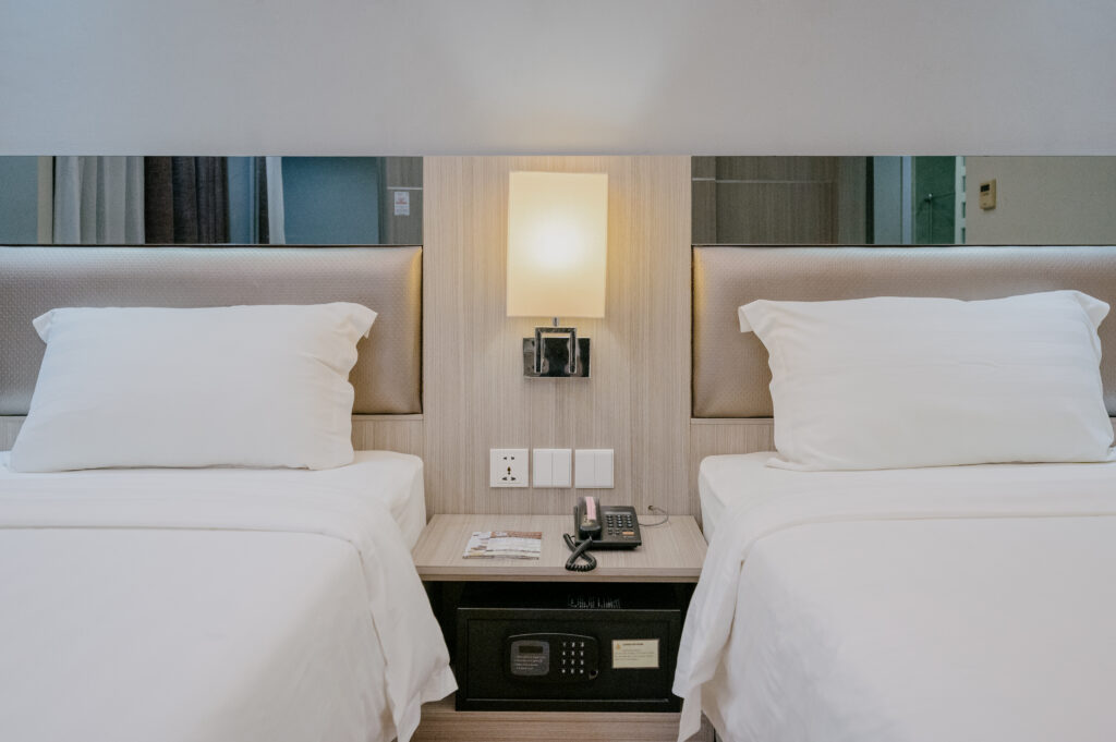 Close-up of beds in Premium Twin Room at Livingston Hotel Sandakan showing bedding details and bedside area