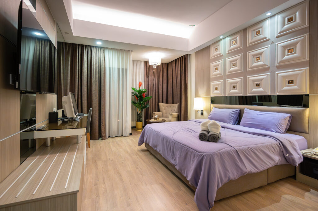 Interior view of Caribbean Suite at Livingston Hotel Sandakan showing bed, sofa, balcony, and elegant decor