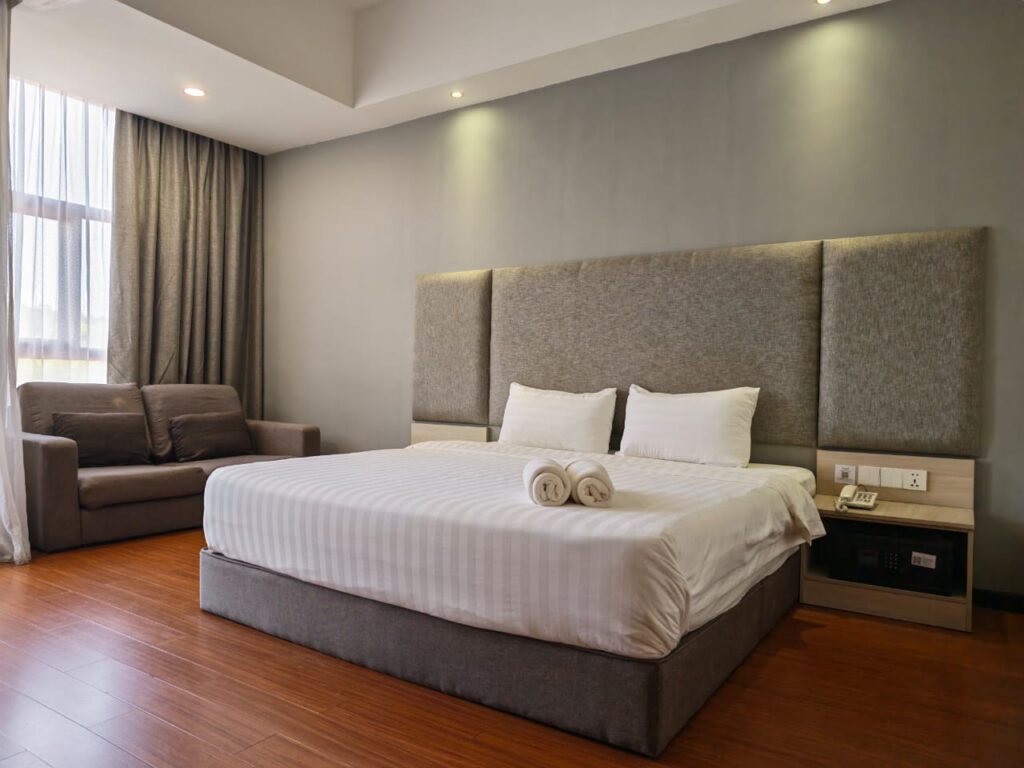 Accessible Deluxe King Room with lowered bed, sofa, bedside telephone, and easy access layout at Livingston Hotel Sandakan Sabah