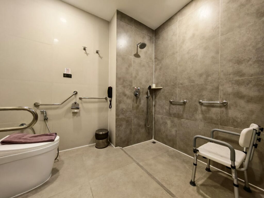 Accessible shower area with grab bars and shower chair for seated bathing at Livingston Hotel Sandakan Sabah